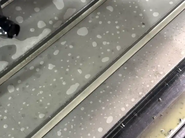 Separated CNC coolant showing unstable emulsion in a machine tray