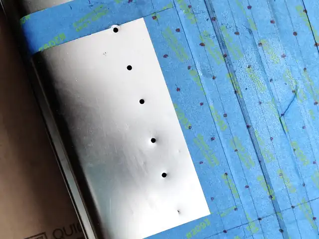 Thin stainless drilling setup with marked holes and backing support concerns