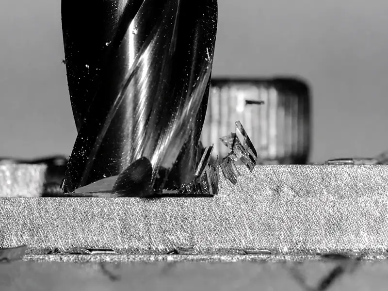 End mill cutting metal with visible chips showing how helix angle affects chip evacuation