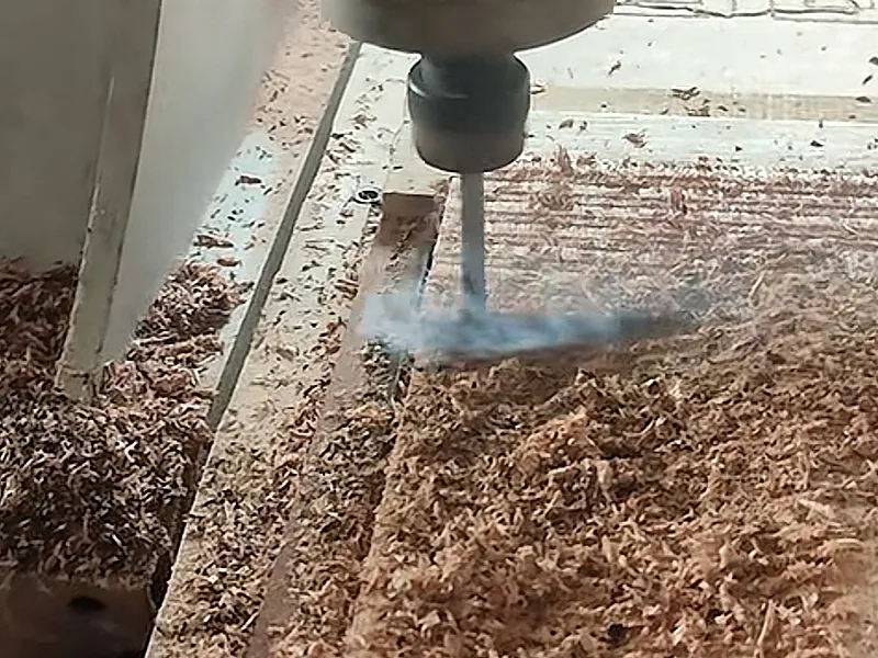Routing a wooden panel with visible loose debris around the cutting area