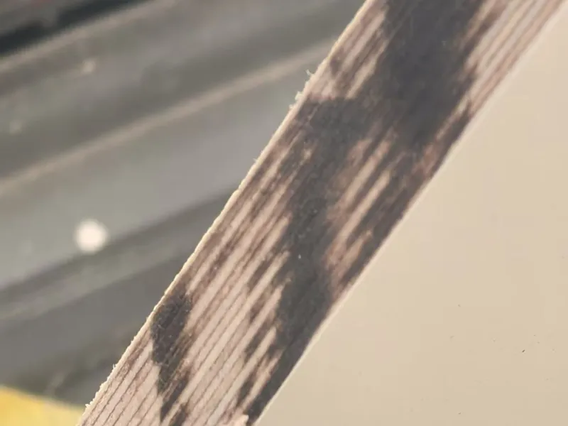 A dark, uneven fibrous area along a wood edge