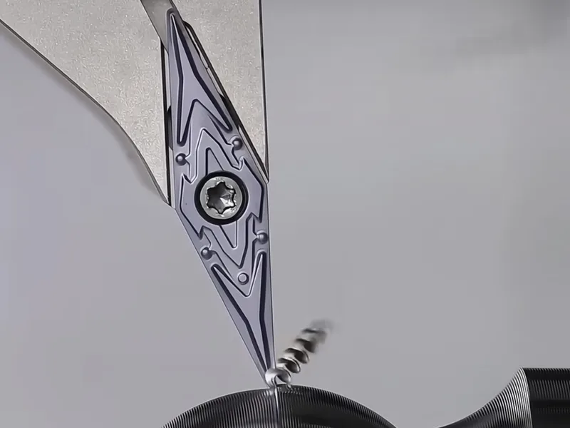 Close view of a pointed turning insert beside a metal workpiece
