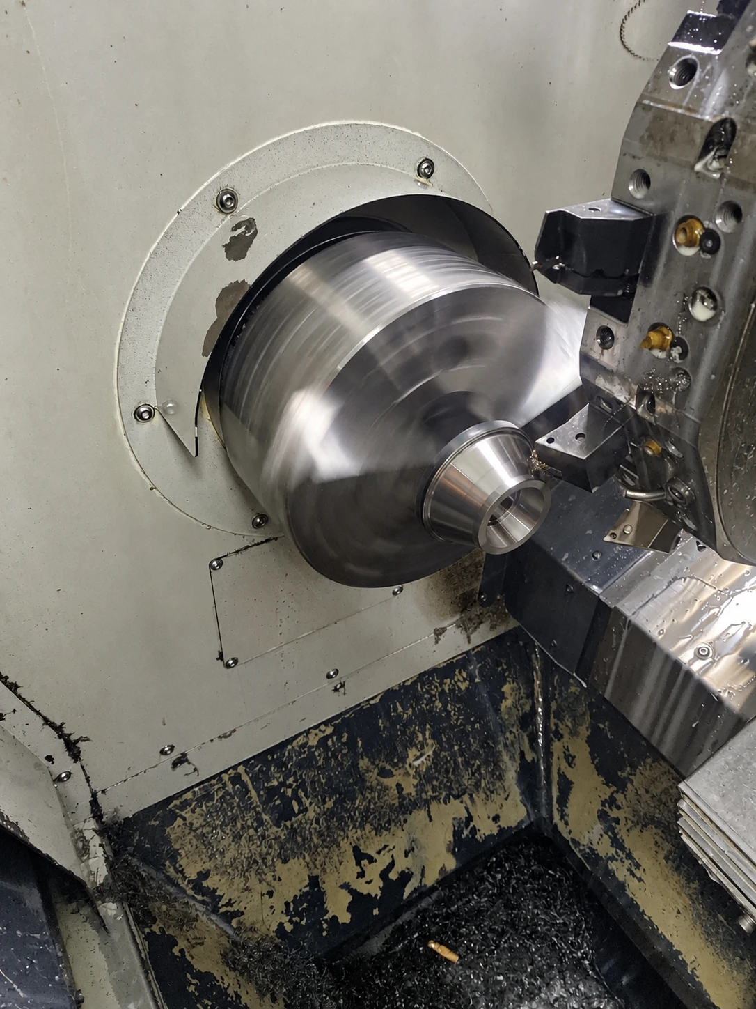 Rotating workpiece beside turret-mounted toolholders inside a lathe.