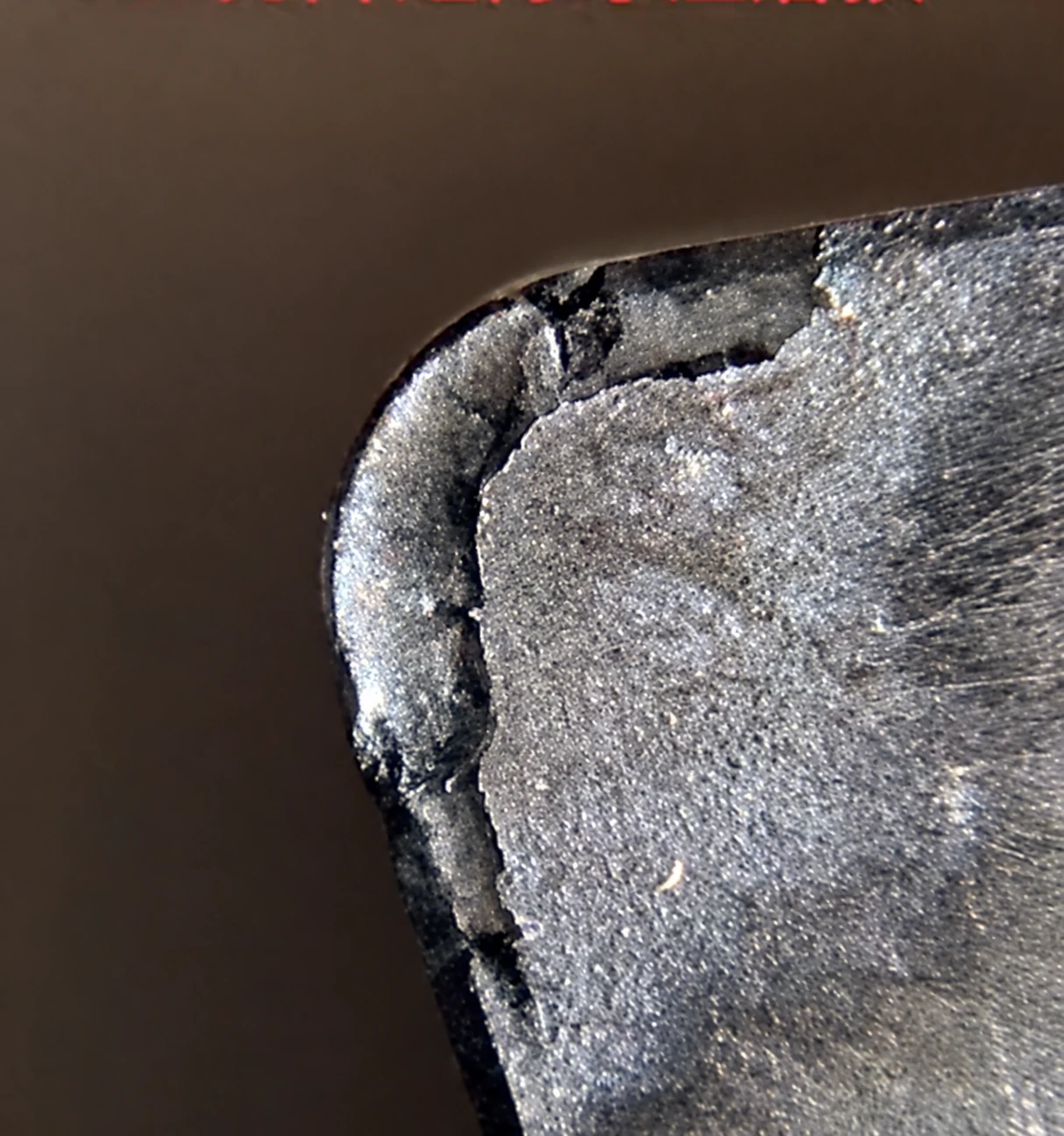 Close-up of a cutting-tool corner with an irregular edge and a dark band along its perimeter.