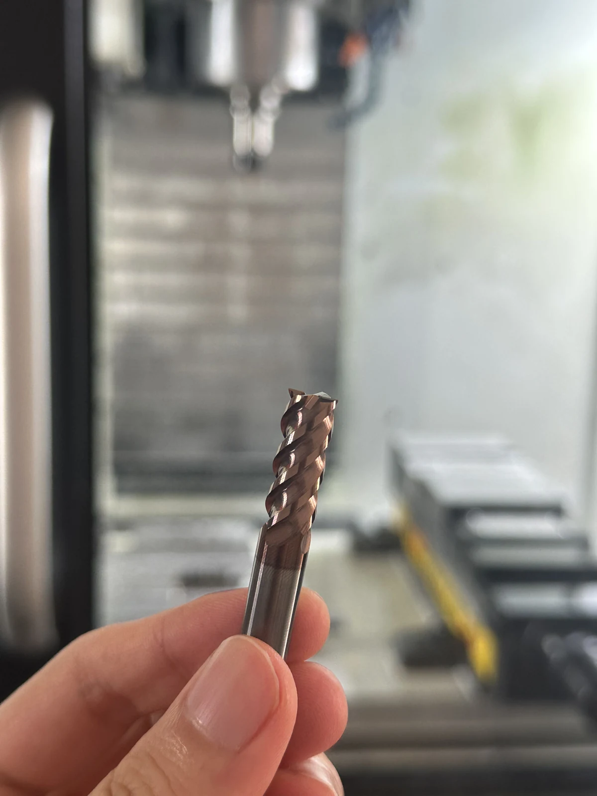 Close-up of an end mill held in front of a CNC machine.