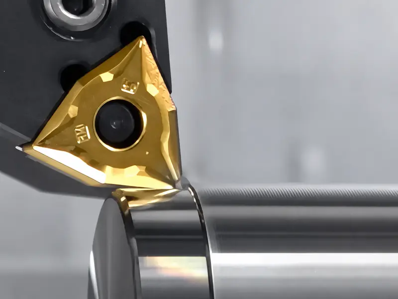 A triangular turning insert beside a cylindrical workpiece