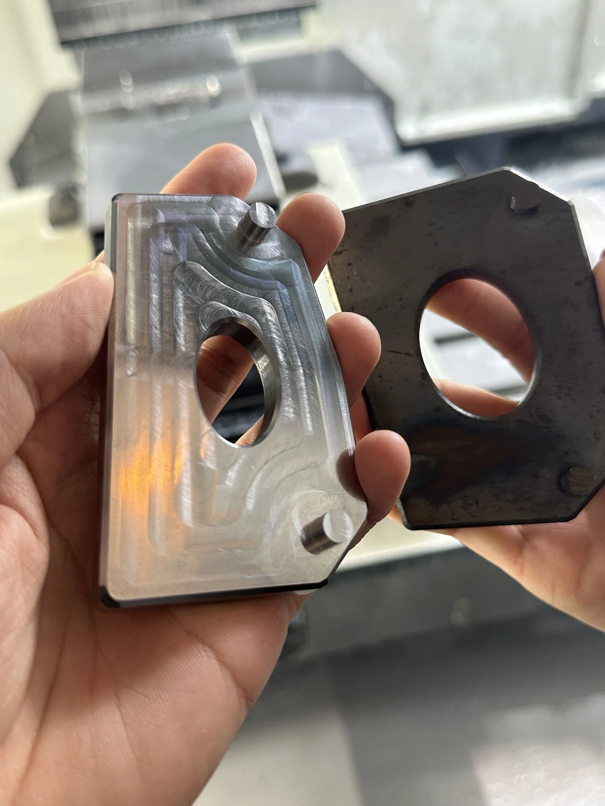 Two metal workpieces held side by side, with visible milled paths on one surface.