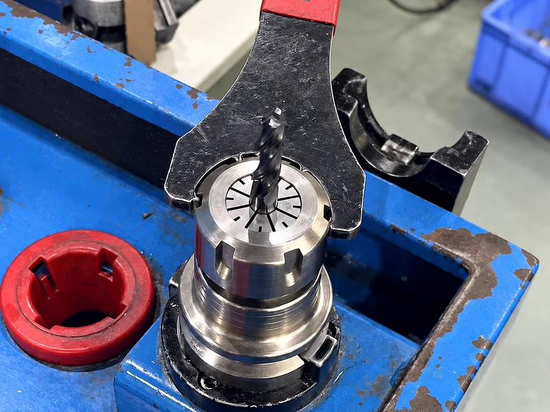 A wrench engaging a toolholder nut in a holding fixture